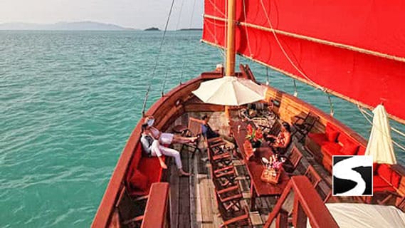 Traditionelle Dschunke mit roten Segeln auf türkisem Wasser im Golf von Thailand