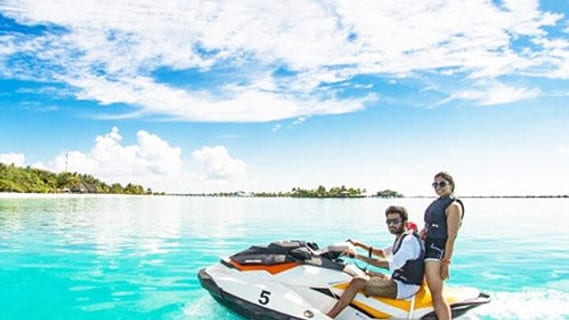 Zwei Personen auf einem Jetski im türkisblauen Wasser vor Koh Samui