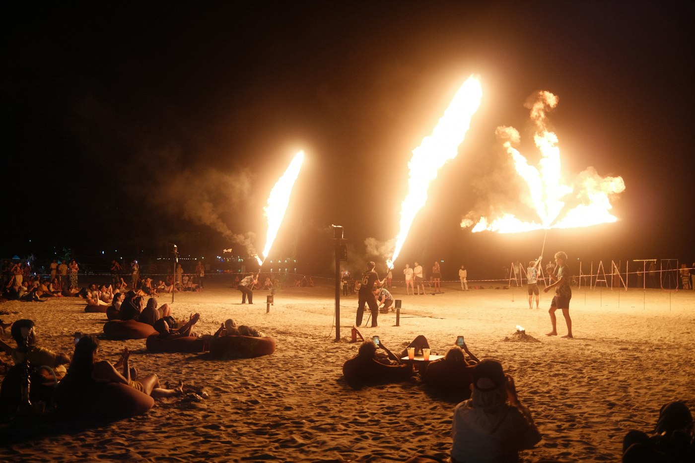 Feuershow und Publikum nachts am Strand
